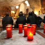 Nel frattempo la chiesa si � riempita di anziane rigorosamente vestite di nero che vanno a riempire il piccolo ambiente illuminato da ceri rossi
